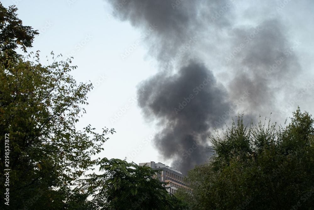 Obraz premium Thick black smoke rises from the top of an apartment building after a drone attack in Ukraine. The concept of fire, missile attack, drone raid