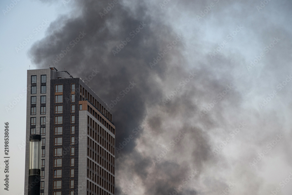 Obraz premium Thick black smoke rises from the top of an apartment building after a drone attack in Ukraine. The concept of fire, missile attack, drone raid