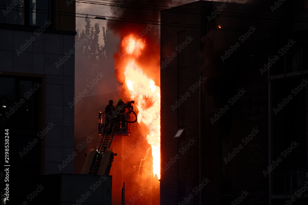 Obraz premium Firefighters put out the burning building of the shopping center. Smoke and fire after a drone attack in Ukraine, rescuers are working at the scene