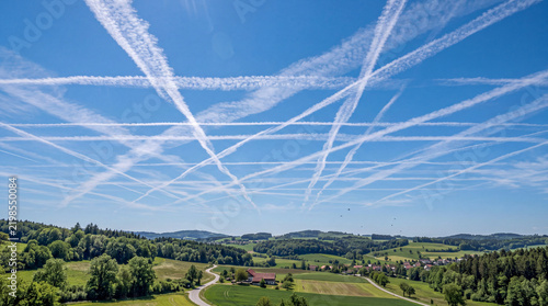 Contrails spread across a blue sky in a rural area