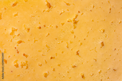 Golden yellow Gouda cheese slice with porous surface texture detail