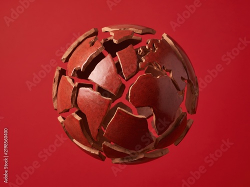 Fragmented ceramic sphere floating on red background