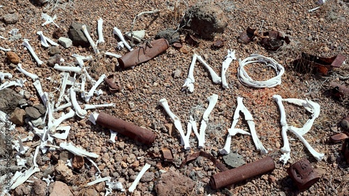 Bones spelling NO WAR on dry, rocky terrain, conveying concepts of peace, anti-war sentiment, and the devastating consequences of conflict and destruction on life and the environment