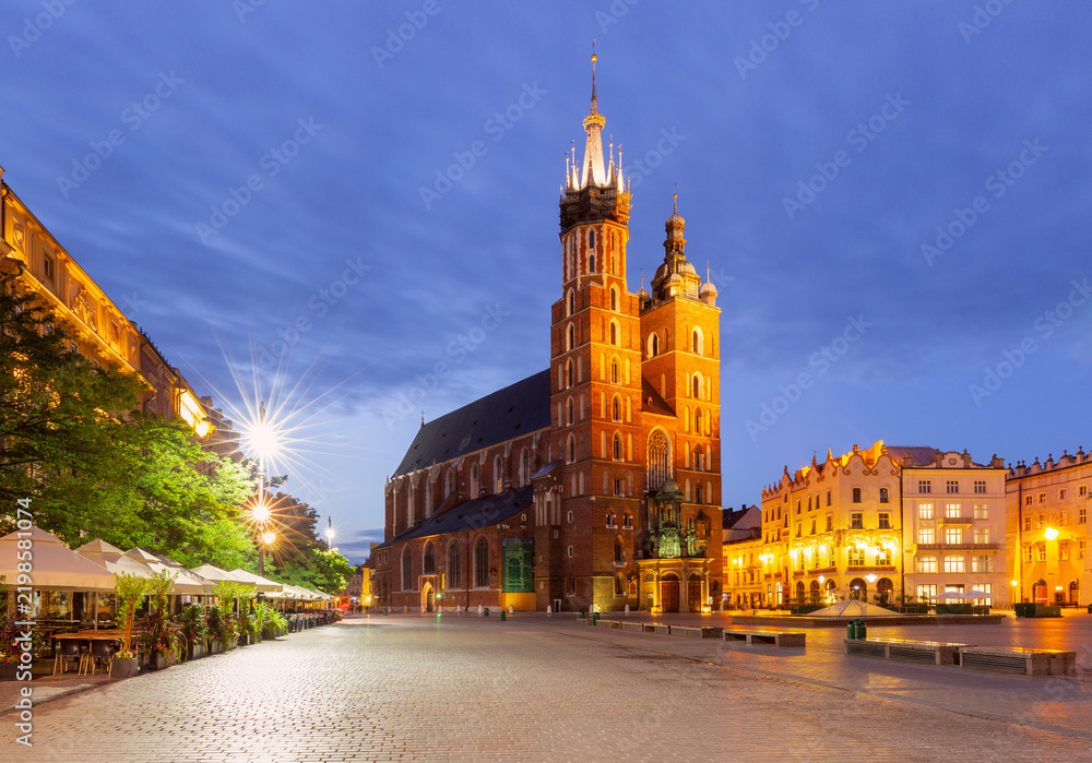 Obraz premium Illuminated St Mary s Basilica and historic buildings on Main Market Square in Krakow, Poland, during blue hour.