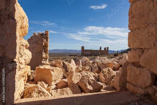 Bild auf Leinwand Sunlit stone ruins and collapsed walls frame desert landscape beneath blue sky a