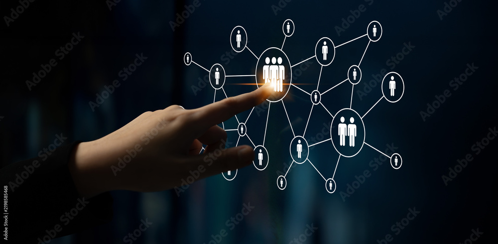 Obraz premium A hand reaches out to select a group of people within a connected digital network, illustrating concepts of interaction, connectivity, and social dynamics in technology. Ledger