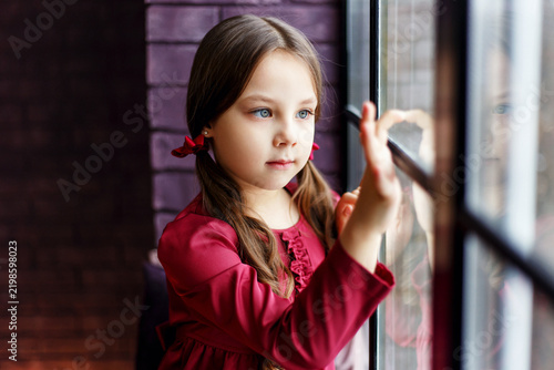 Young Girl in Red Dress Looking Out Window