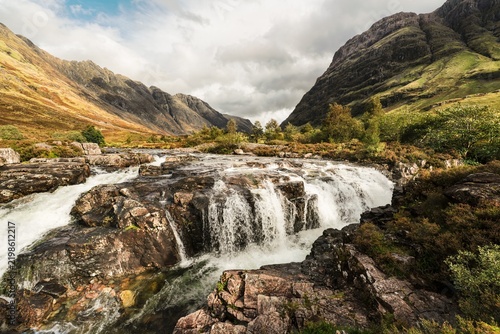 A panoramic view of a waterfall, during an early morning autumn hike in Scotland highlands, along the River Coe in Glencoe, UK