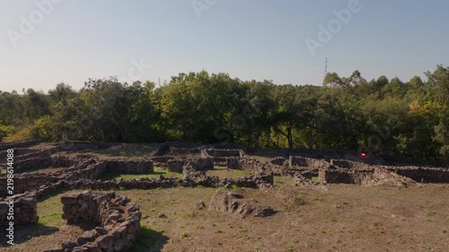 Ancient stone ruins of Castro de Romariz archaeological site nestled in a lush green Portuguese forest.