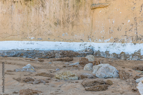 Old stone wall built directly on rocky beach sand