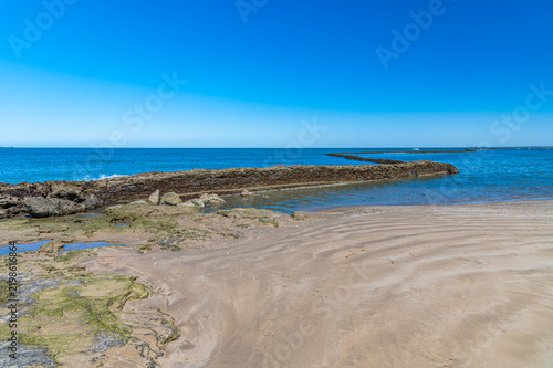 Beach in Chipiona with rocks in foreground, Cadiz, Spain