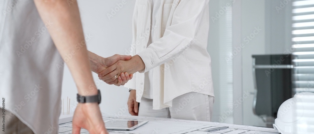 Obraz premium Architects and clients shaking hands in office, establishing a new construction project partnership, securing a successful business deal, and building trust in design