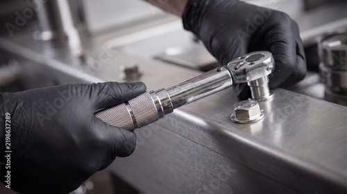 Technician hand holding tightening stainless torque wrench tool machine bolt fastening metal industrial professional focus task