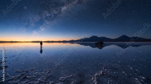 Person and vehicle on uyuni salt flats at night