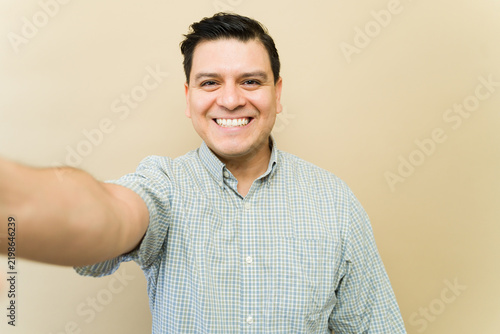 Adult man taking a selfie, smiling broadly and enjoying the moment with a cheerful expression
