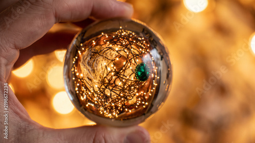 Hand holding glowing Christmas ornament with fairy lights