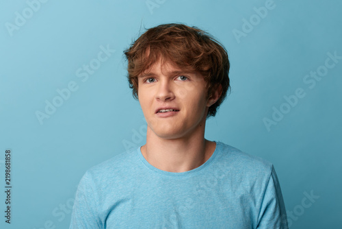 Fotografie Young man with a hesitant uncertain expression looking aside