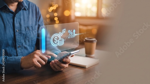Man using smartphone with digital finance and investment holograms at a table.
