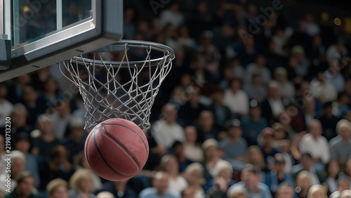 Basketball ball swishing through hoop net during competitive game in indoor arena