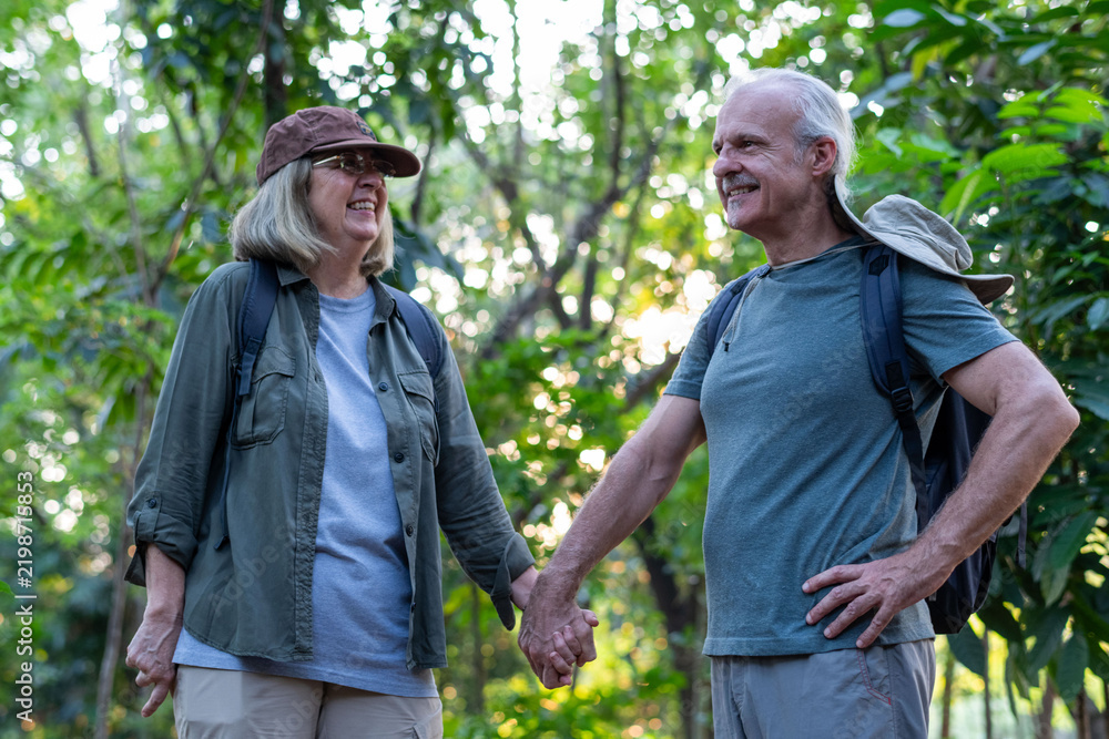Obraz premium Happy seniors hiking together outdoors.