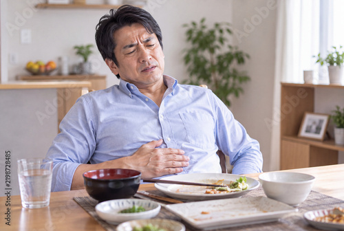 Tapety artystyczne 食後に胃もたれを感じてお腹を押さえる中年男性