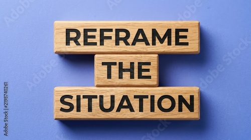 Wooden blocks featuring reframe the situation text displayed against a solid vibrant light blue backdrop surface