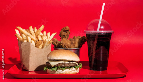 Classic Fast Food Combo with Cheeseburger, Crispy Chicken, French Fries and Soft Drink on a Red Tray
