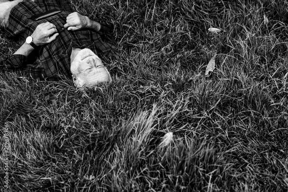 Obraz premium Elderly man relaxing on grass in black and white photo
