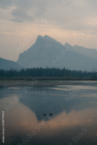 Mount Rundle reflected in the still water of Vermilion Lakes through wildfire smoke haze near Banff, Alberta, Canada