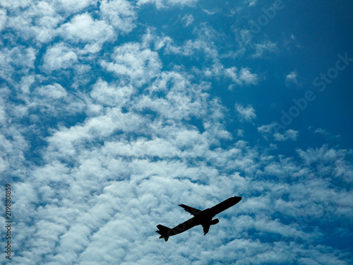 Quadro su tela Commercial airliner silhouetted against a textured blue sky filled with white altocumulus clouds
