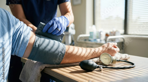 Doctor checking patient blood pressure in clinic with medical device