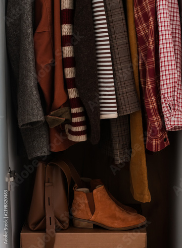 Women’s autumn and winter clothing, shoes, bags in the wardrobe on a hanger. Cozy seasonal clothing concept