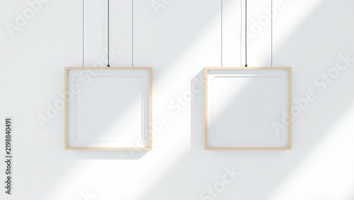 Two blank square wooden picture frames hanging on a bright wall