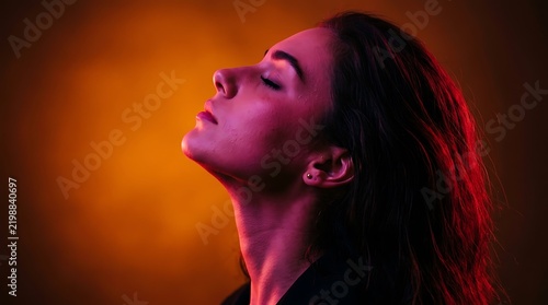 Stunning portrait of a young woman with vibrant red and orange studio lighting illuminating her profile
