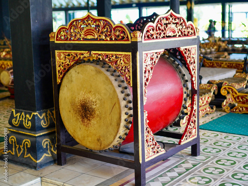 A detailed cultural shot of a traditional Indonesian musical instrument known as the kendang, featuring classic woodcraft and leather skin set on a vintage tile floor inside a historic palace