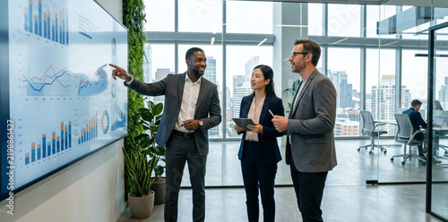 Diverse business team analyzing financial charts on a large screen in modern office