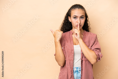 Photography Young woman isolated on beige background pointing to the side and doing silence