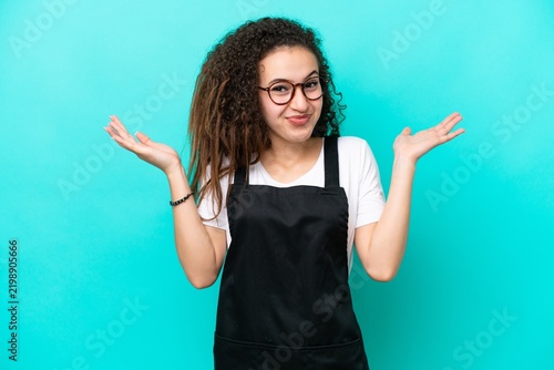 Quadro su tela Restaurant waiter Arab woman isolated on blue background having doubts while rai
