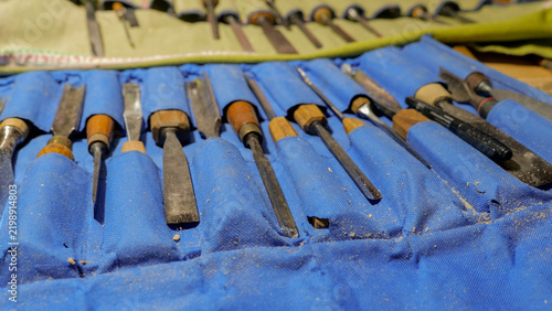Konstfotografi Set of woodcarving chisels and gouges arranged in blue fabric roll with wood sha