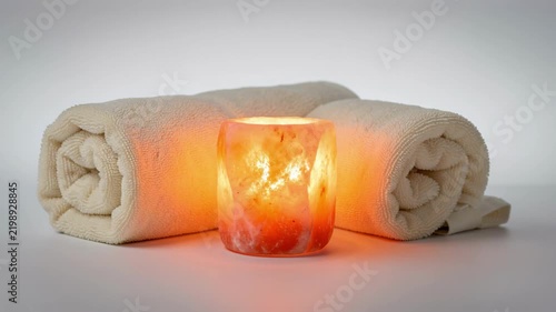 Relaxing Spa Candle Beside Rolled Towels.