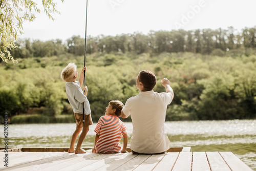 Joyful fishing moments by the serene lake with family on a sunny afternoon