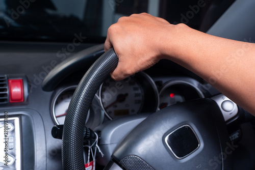 Fotografie Close up of driver hand holding the steering wheel while driving car with speedometer instrument cluster in background