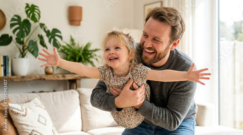 Father playing with daughter, laughing and smiling, indoors, happy family moments