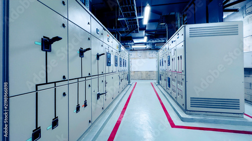 Electrical control panel room in industrial plant with switchgear cabinets, power distribution, and red safety line.