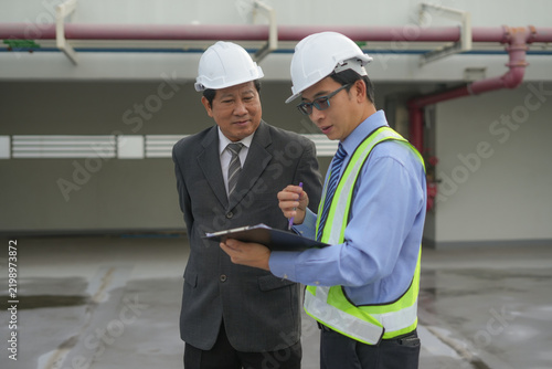 Engineer inspector hardhat safety vest clipboard factory industrial inspection during site walkthrough, adult men reviewing checklist and discussing compliance, risk management, and workplace