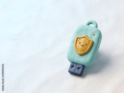 Stylized USB security key with smiling shield emblem, clay texture, pastel colors, wide copy space.