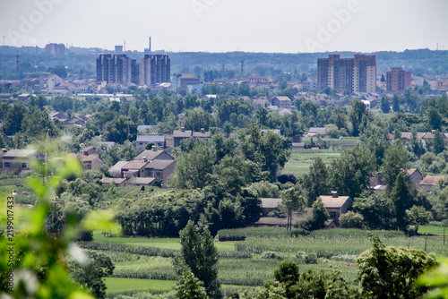Fotografie Panoramic Rural Suburb and Farmland Beside Modern Town Skyline