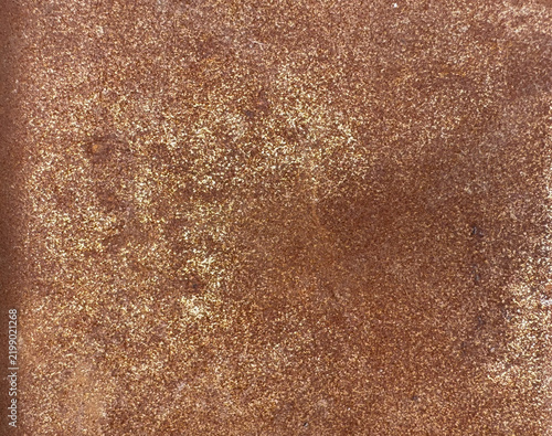 Close-up of golden rusty metal surface with grainy texture