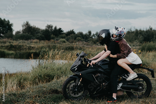 couple of bikers in helmets riding classical motorcycle on country road