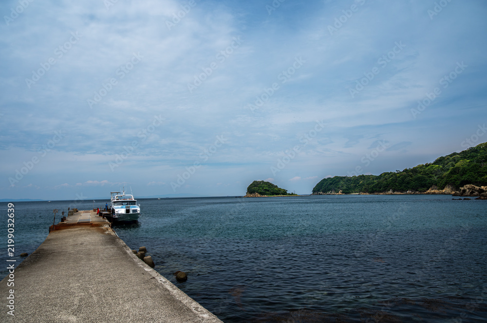 Obraz premium 海へ続くコンクリートの桟橋と停泊する客船、穏やかな海と島々の風景